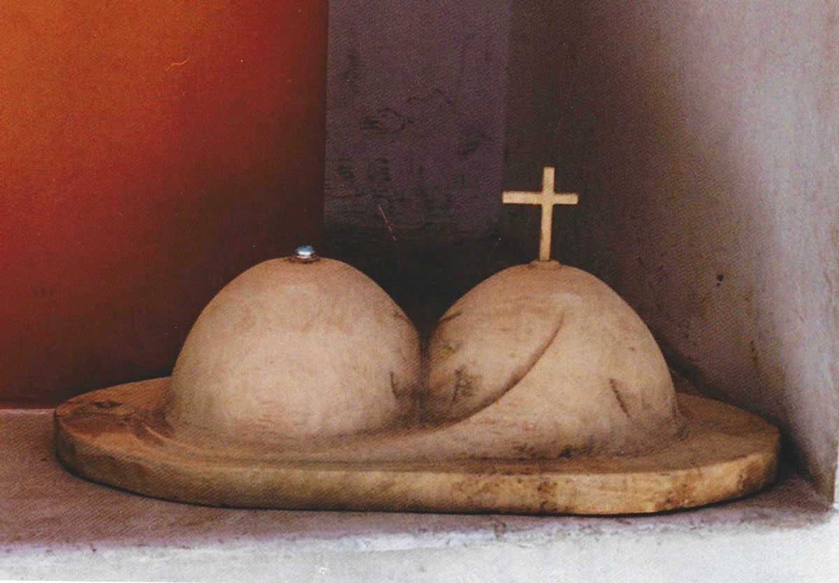 Zweikammergehirn von H. Schero: Steinskulptur mit geteiltem Kopf und Kreuz